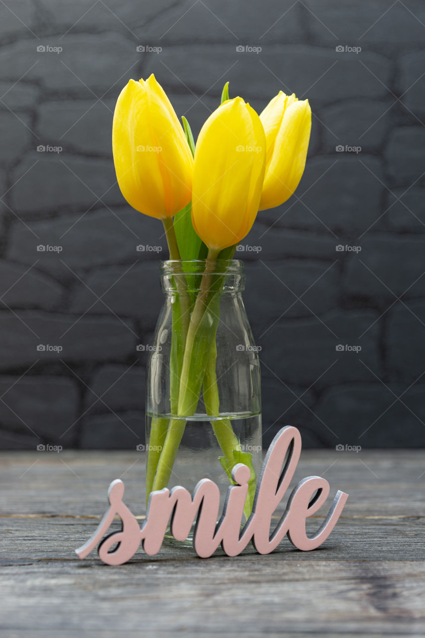 three yellow tulips in a vase and the word smile