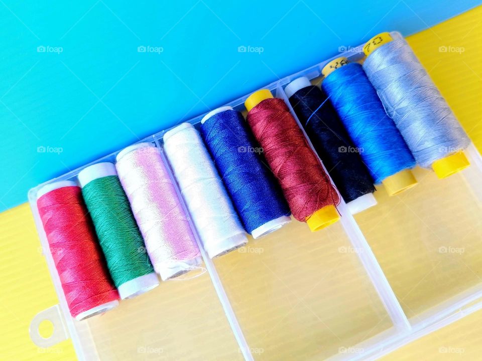 Colourful threads in the box on yellow and blue background.