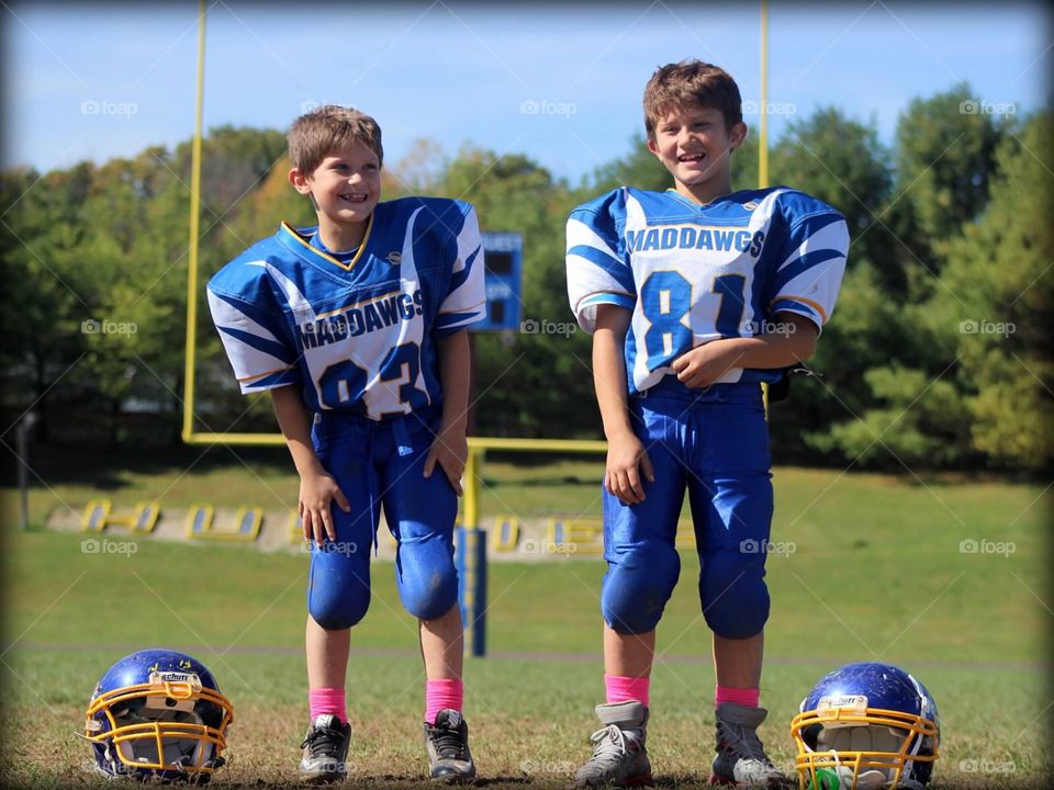 Football Brothers . Two handsome young brothers, suited up in their football uniforms. 