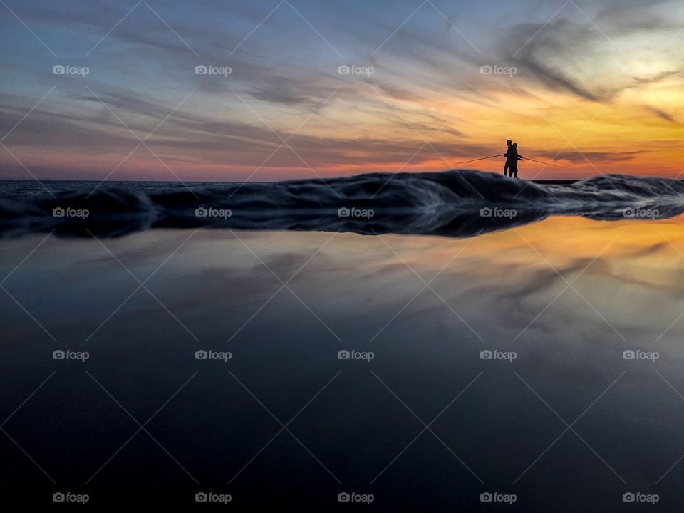 Silhouettes of fishermen fishing on the sea 