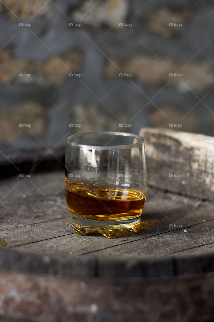 glass of whiskey. glass with neat whiskey no ice on wooden barrels