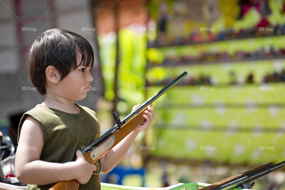 kid at fun fair with toy gun. aim shooting range