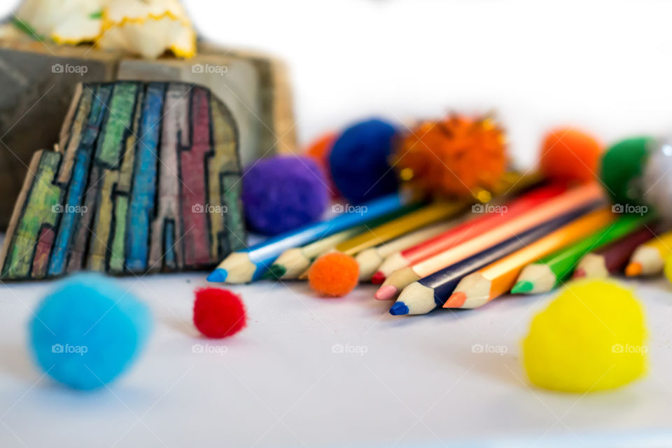 Crayons and fluffy little balls in white background