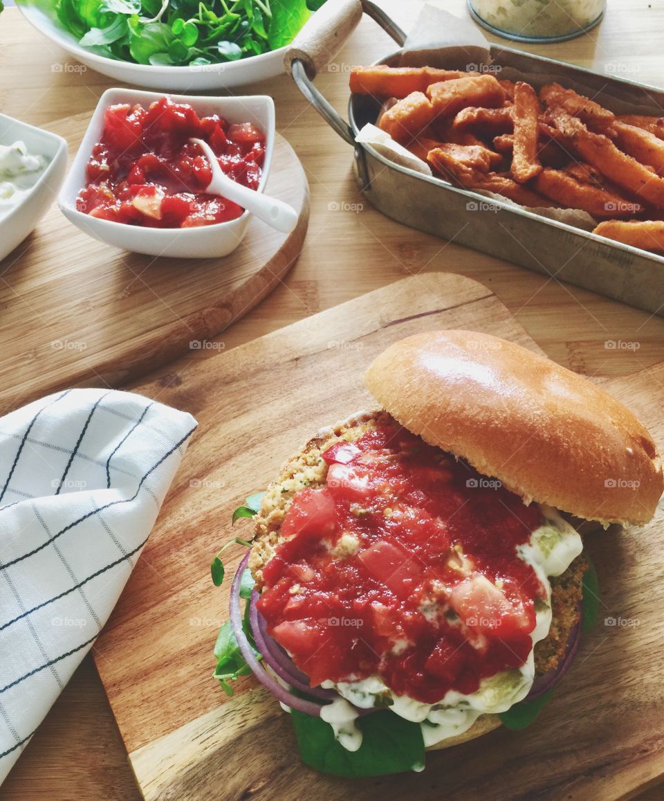 Spicy bean burger with tomato relish and sour cream served with sweet potato fries 