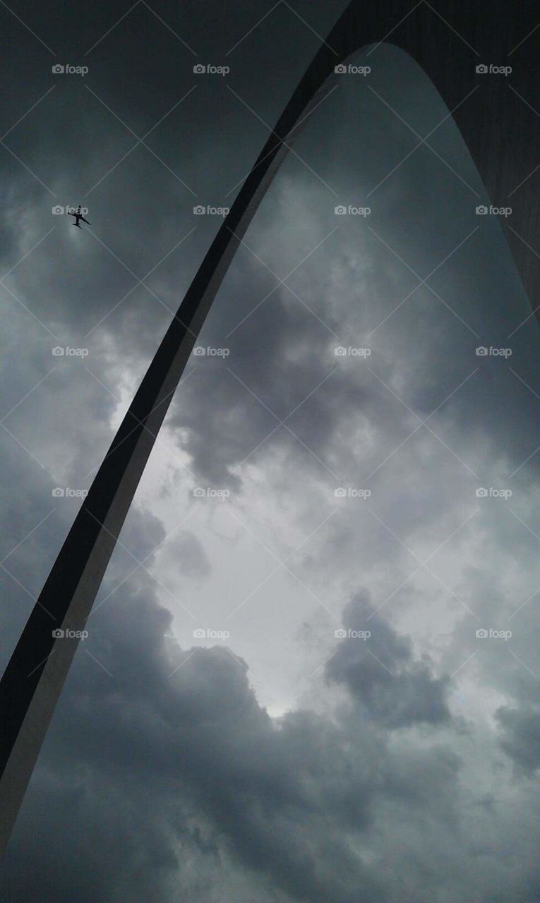 Under the Arch. under the arch in St. Louis, looking up at the plane and incoming storm😊