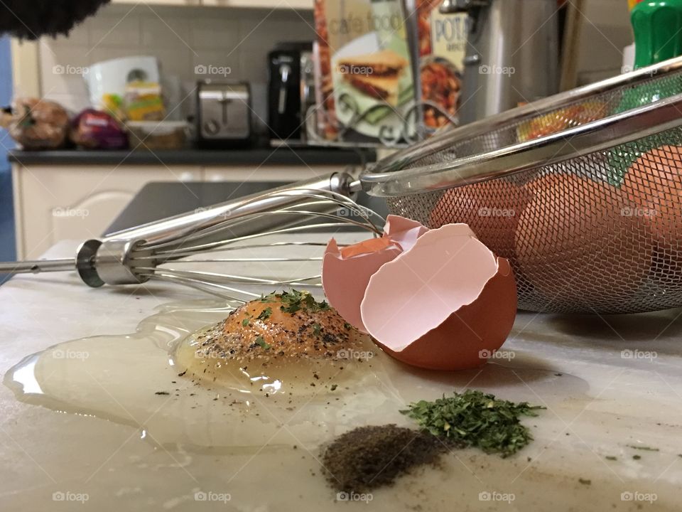 Farm fresh raw cracked brown egg and yolk on kitchen counter foreground closeup 