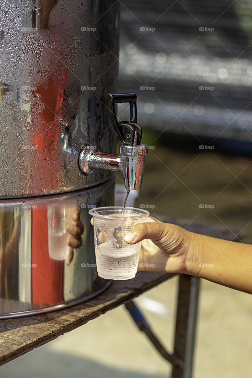 Hand boy holding the glass with water from the water cooler.