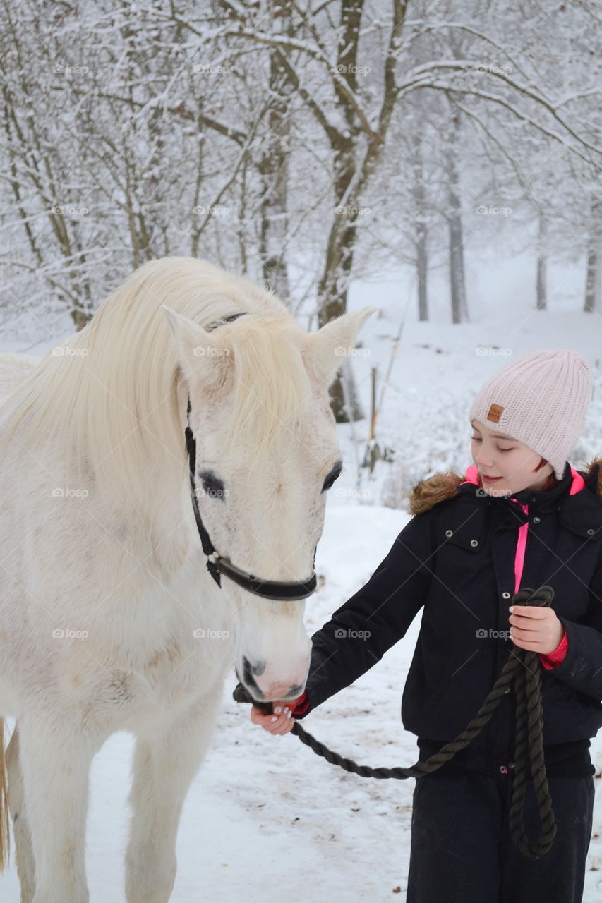 Girl standing near horse in winter