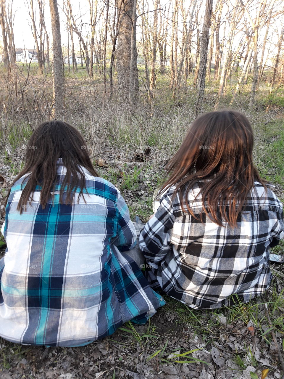 Rear view of two girls sitting in the forest