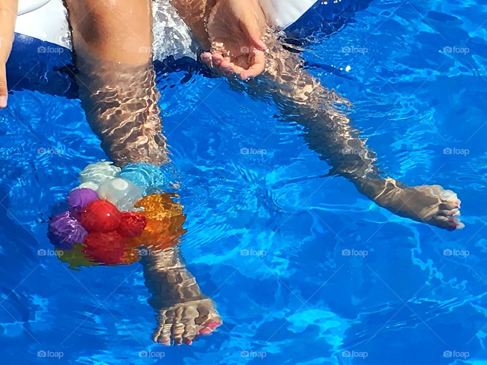 Dangling legs poolside. Legs in the swimming pool