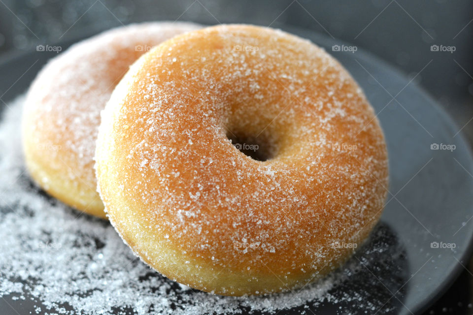 Sugar donut on black plate.