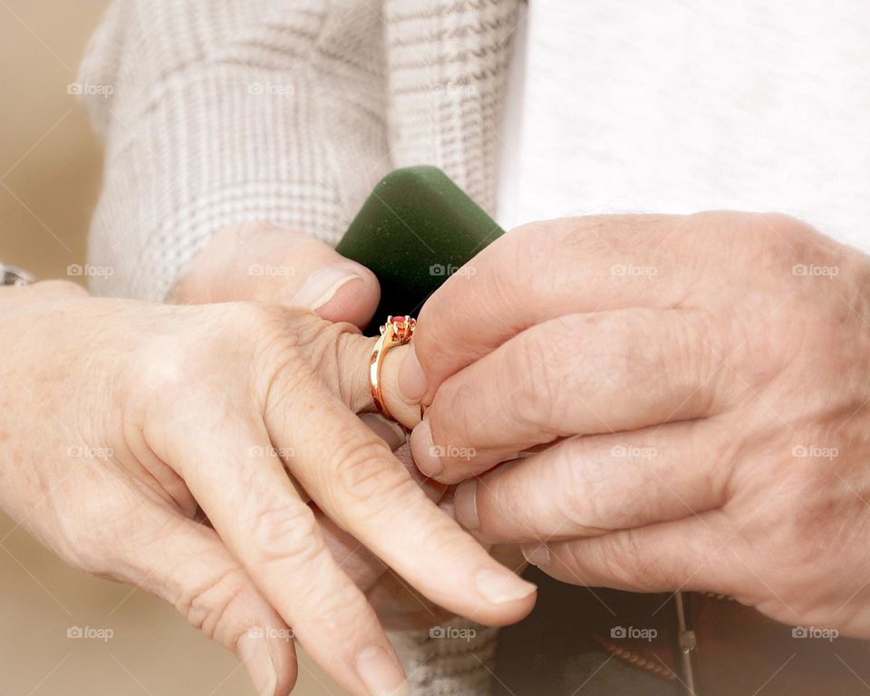 Vintage style photograph of an elderly man placing a ring on the finger of an elderly woman