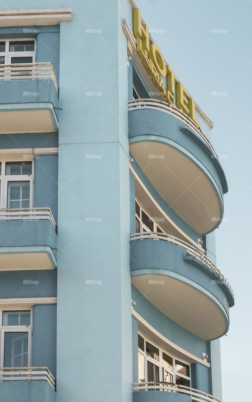 The corner of a pastel blue Art Deco hotel, against a clear blue sky. Leiria, Portugal