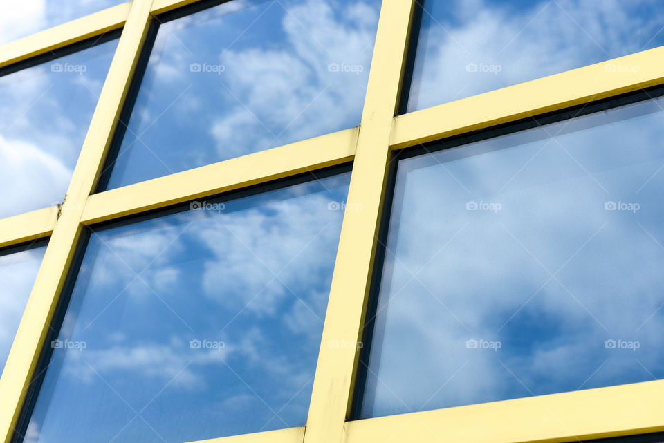 Reflection of clouds in the sky on square windows of a building outdoors