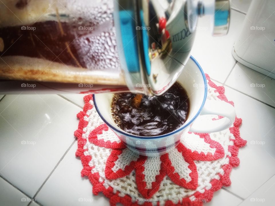 Pouring my french press coffee into my favorite mug sitting on a red and white doily is part of my daily routine