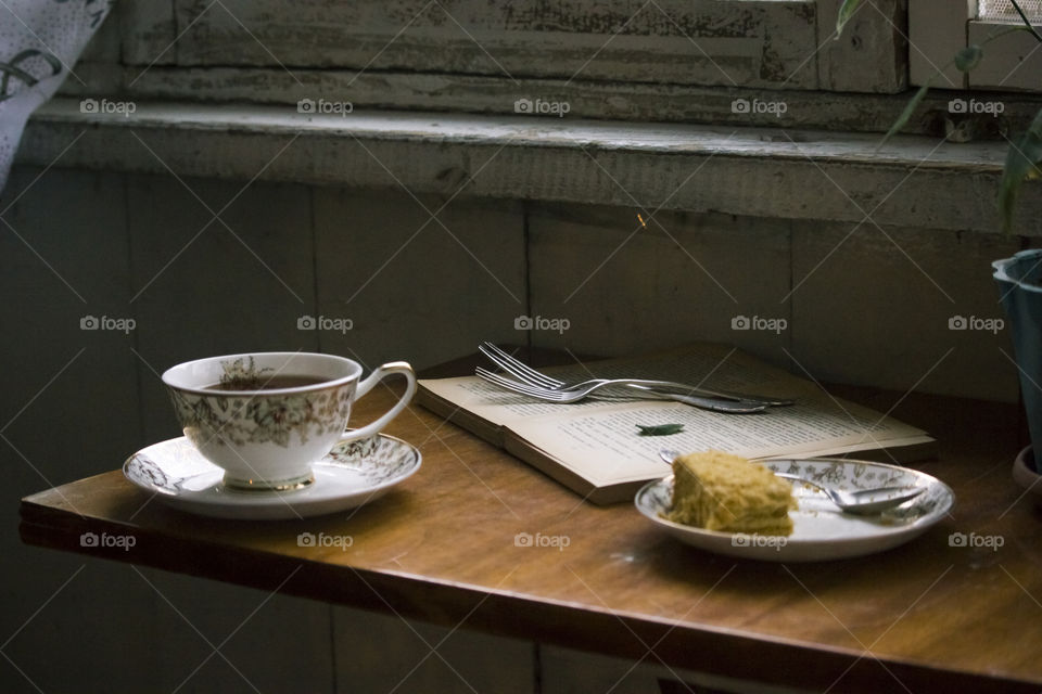 a cup of tea,  slice of cake and book.on.the table
