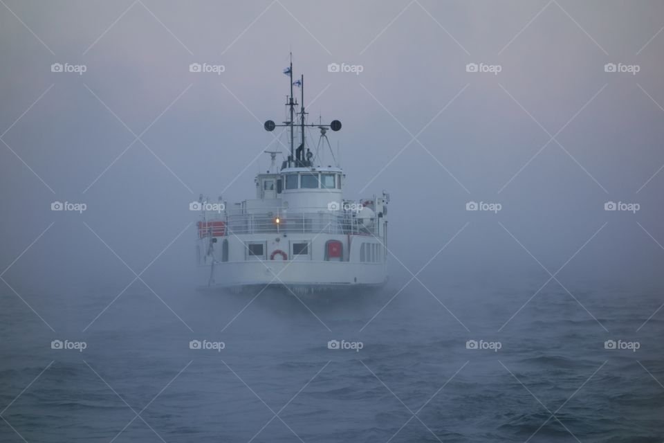 Ferry departing Suomenlinna fortress island on Baltic sea in midst of thick sea smoke or fog on extremely cold January morning at dawn in Helsinki, Finland on 5 January 2016.