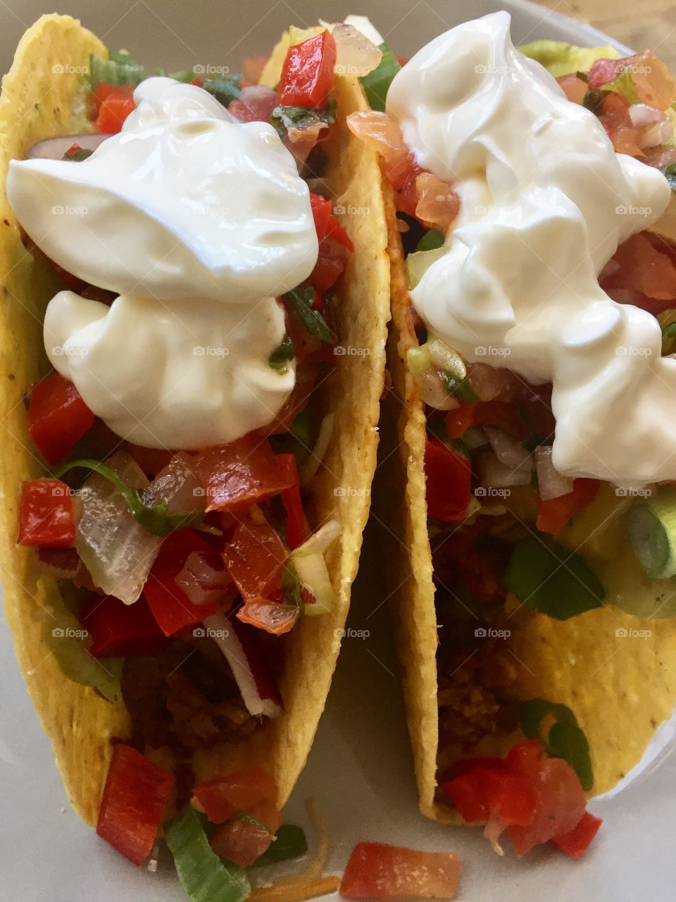 Taco lunch or dinner plate with tomatoes onions guacamole and sour cream on a crispy cornflour shell yum!