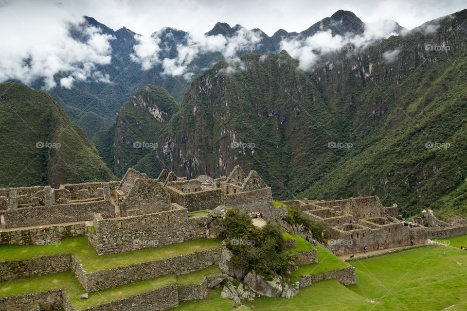 Famous Machu Picchu ruins . Machu Picchu ruins against mountains in the background. Steep slopes and misty mountains. Flat grassland