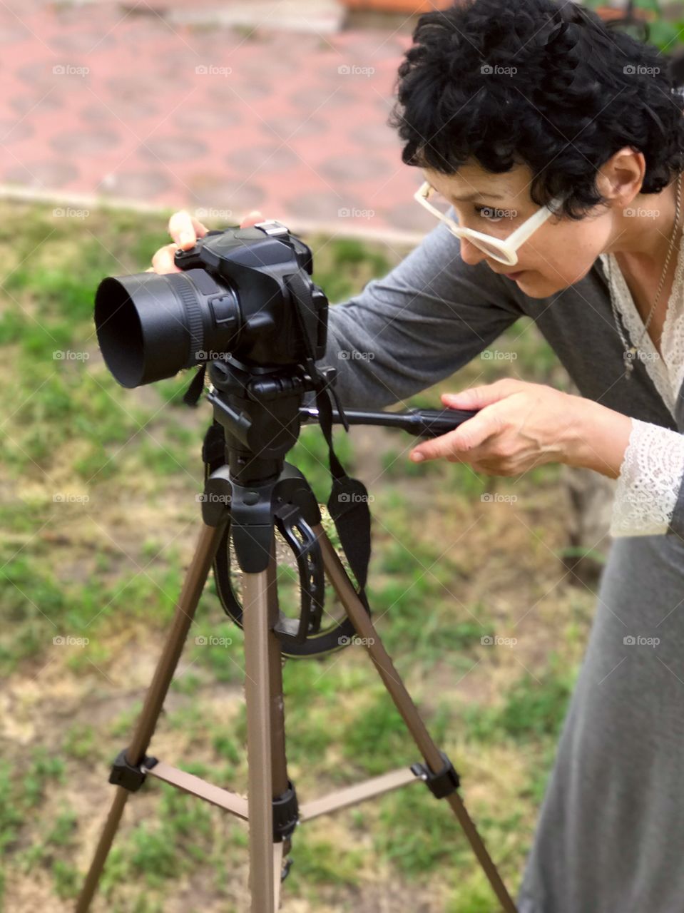 Woman adult in glasses taking photos with a tripod. 