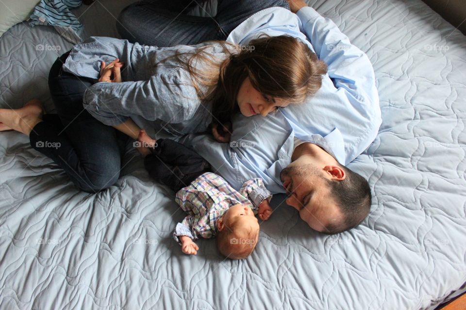 Loving couple with their baby on bed