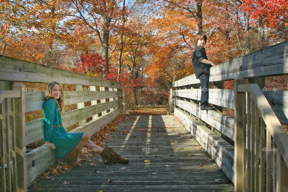 Happy girl and boy sitting on wooden bridge