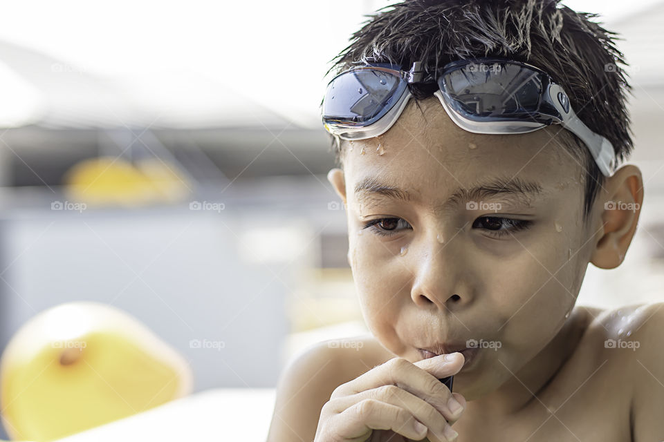 Portrait Asian boy holding Drinking straws and wearing swimming goggles