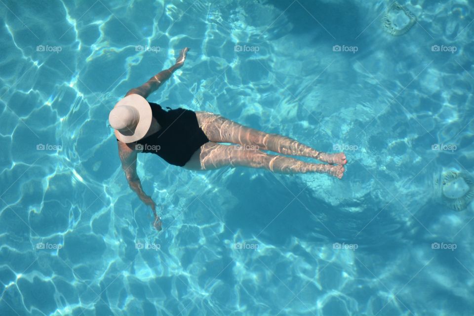 A lady enjoys a refreshing dip in the swimming pool. 