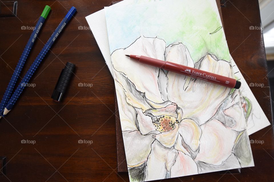 Watercolor sketch of flower on Wood table and sketchbook with colorful Faber-Castell PITT Artist pens and Art Grip Pencils 