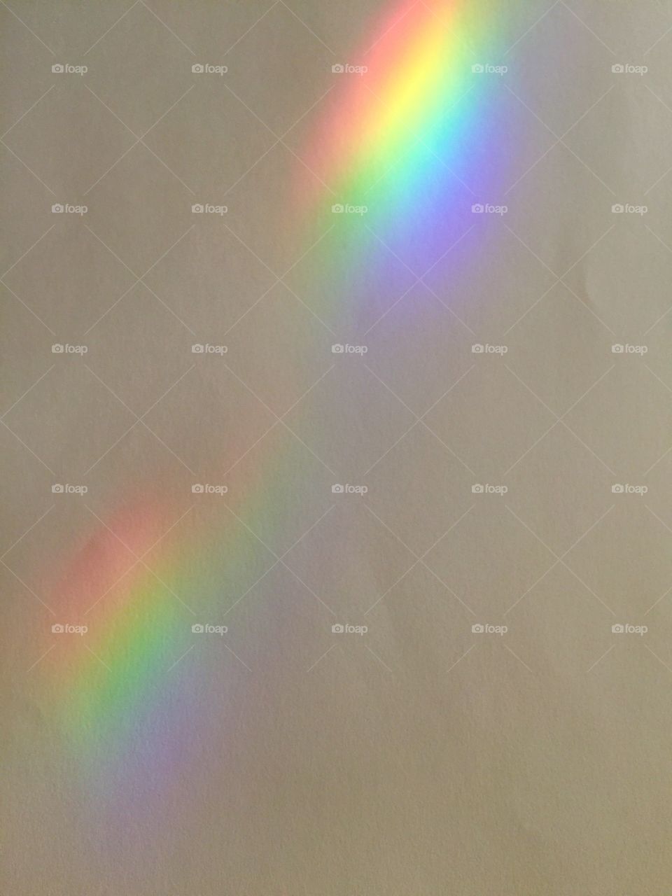 A colorful rainbow against a tan wall.