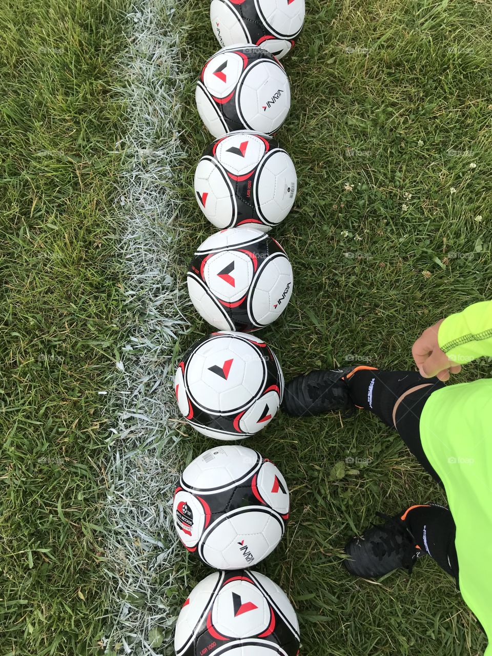 Soccer player standing beside some soccer balls