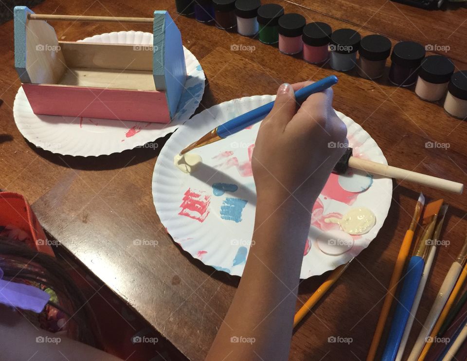 A child at work painting a wooden box