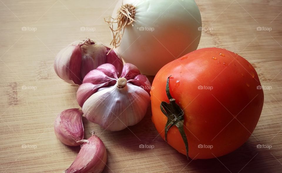 Onion with garlic and tomato on wood