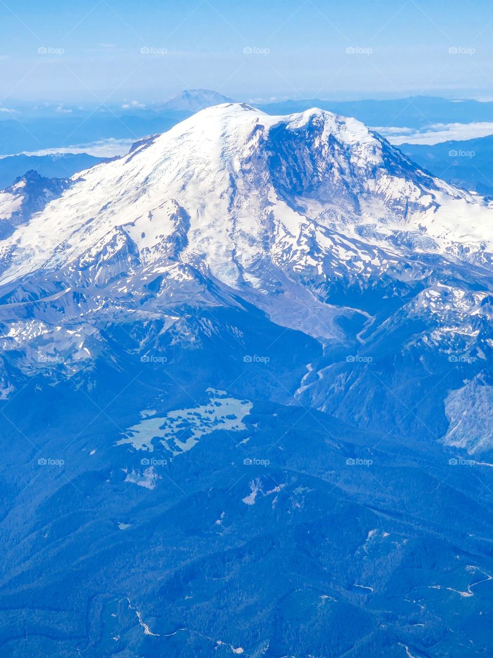 Beautiful Mount Rainier shines like a gorgeous diamond against a darker tree shrouded landscape on a flight headed for Seattle