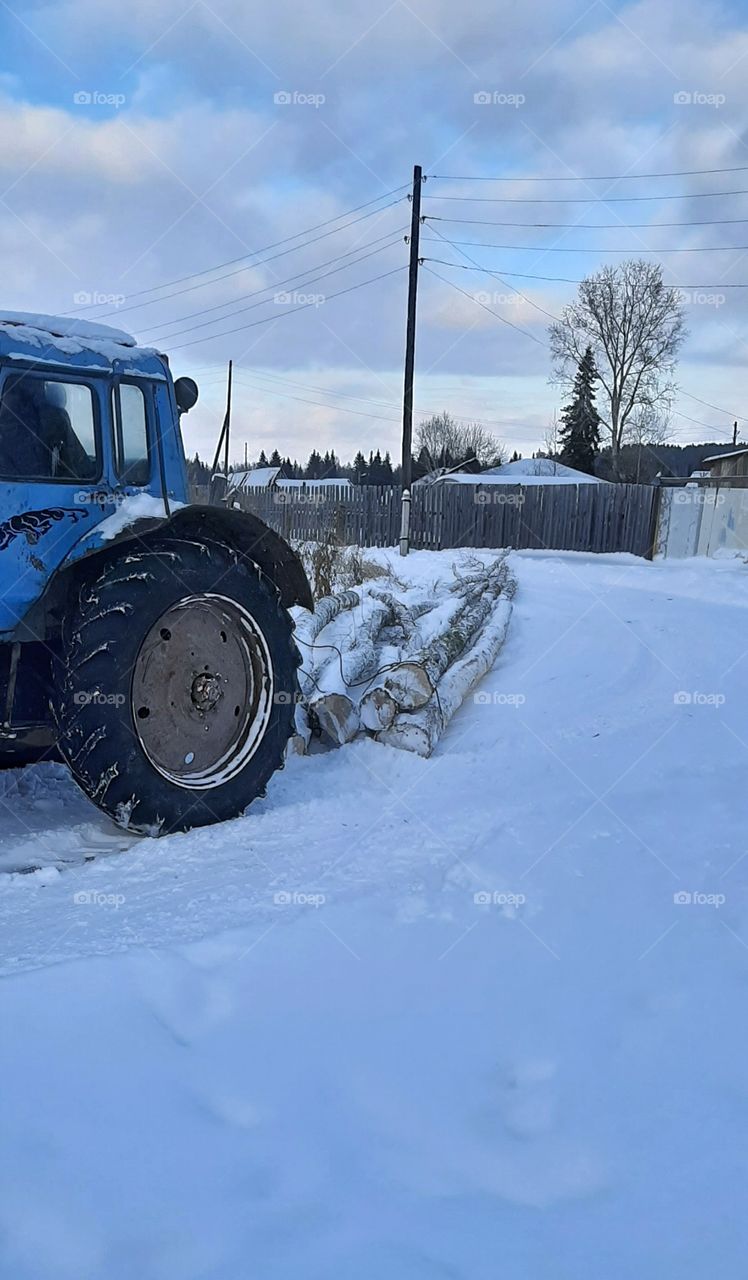 трактор везет дрова по зимней дороге