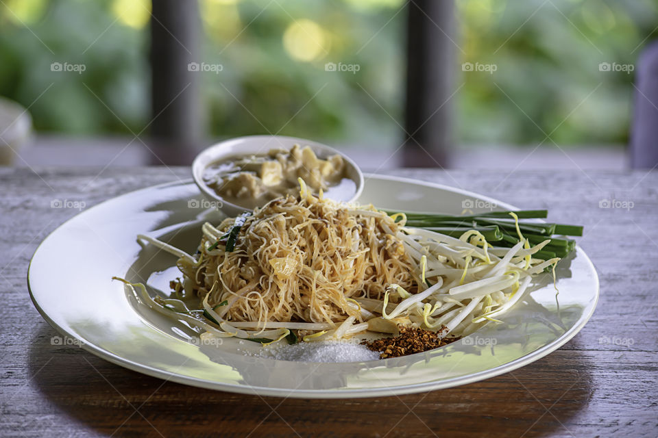 Fried noodle with spring onion and bean sprouts on white plate with garnish.