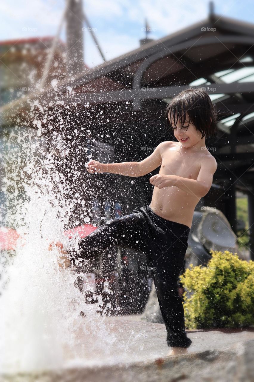 Energetic young boy splashes in the child friendly fountains at Point Ruston, Tacoma, Washington 