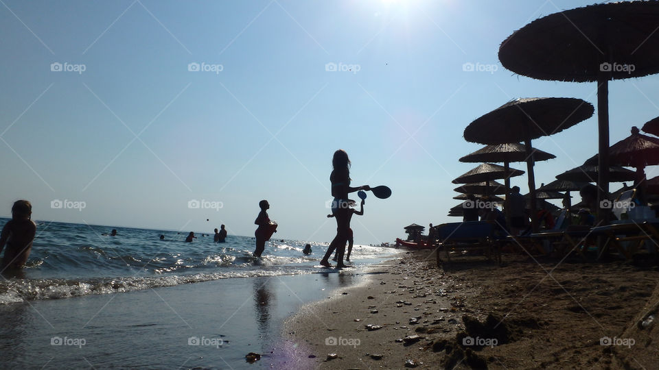 children playing beach ball besides sea