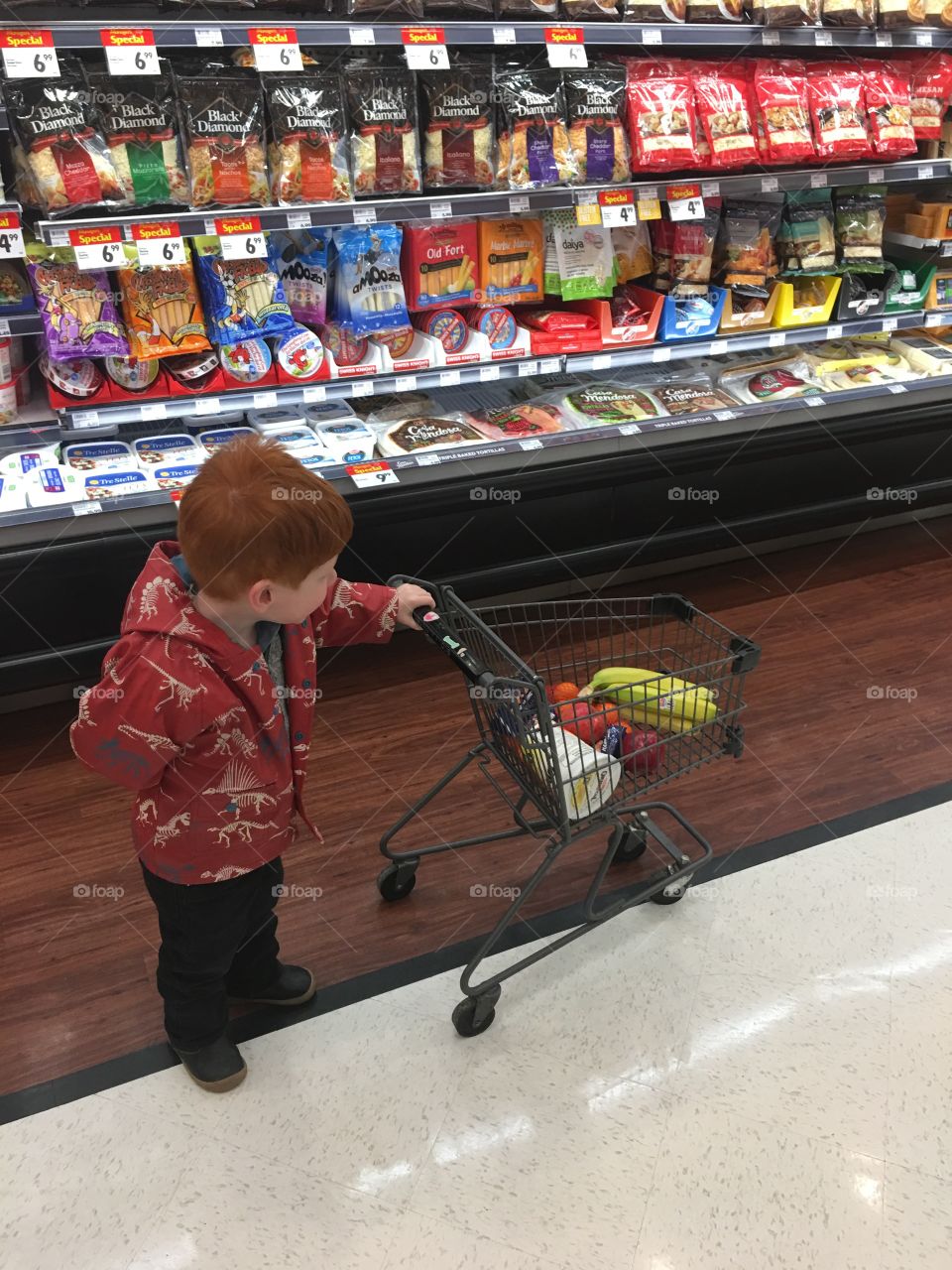 Toddler having fun grocery shopping. Showing off his groceries. 