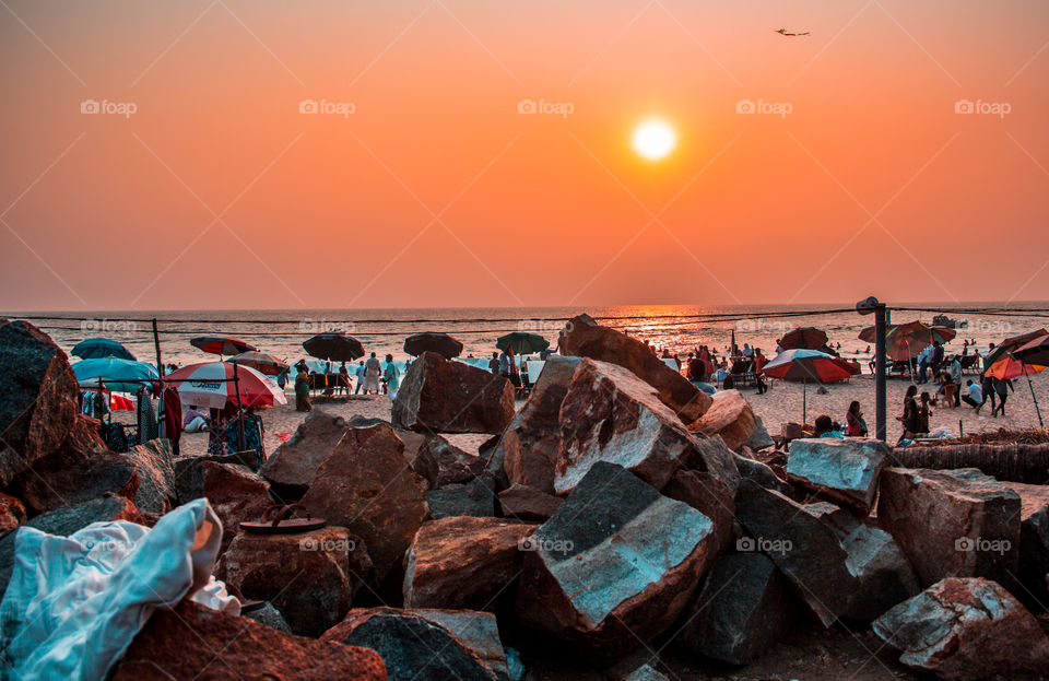 FEBRUARY 18, 2018 A PICTURE OF A SUNSET WITH ROCKS AND UMBRELLAS IN FOREGROUND AT KERALA, INDIA 