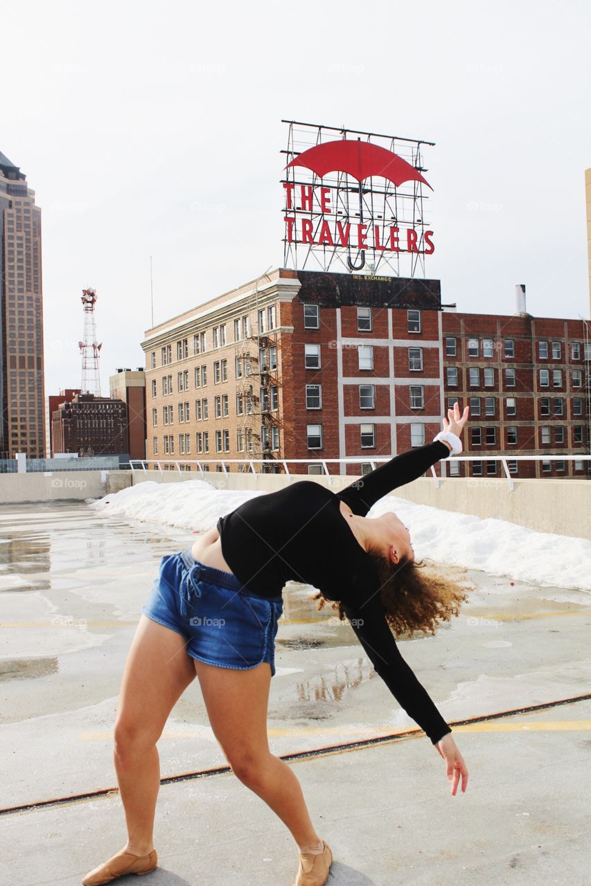 A girl dancing on top of a rooftop on a cold winter day. 