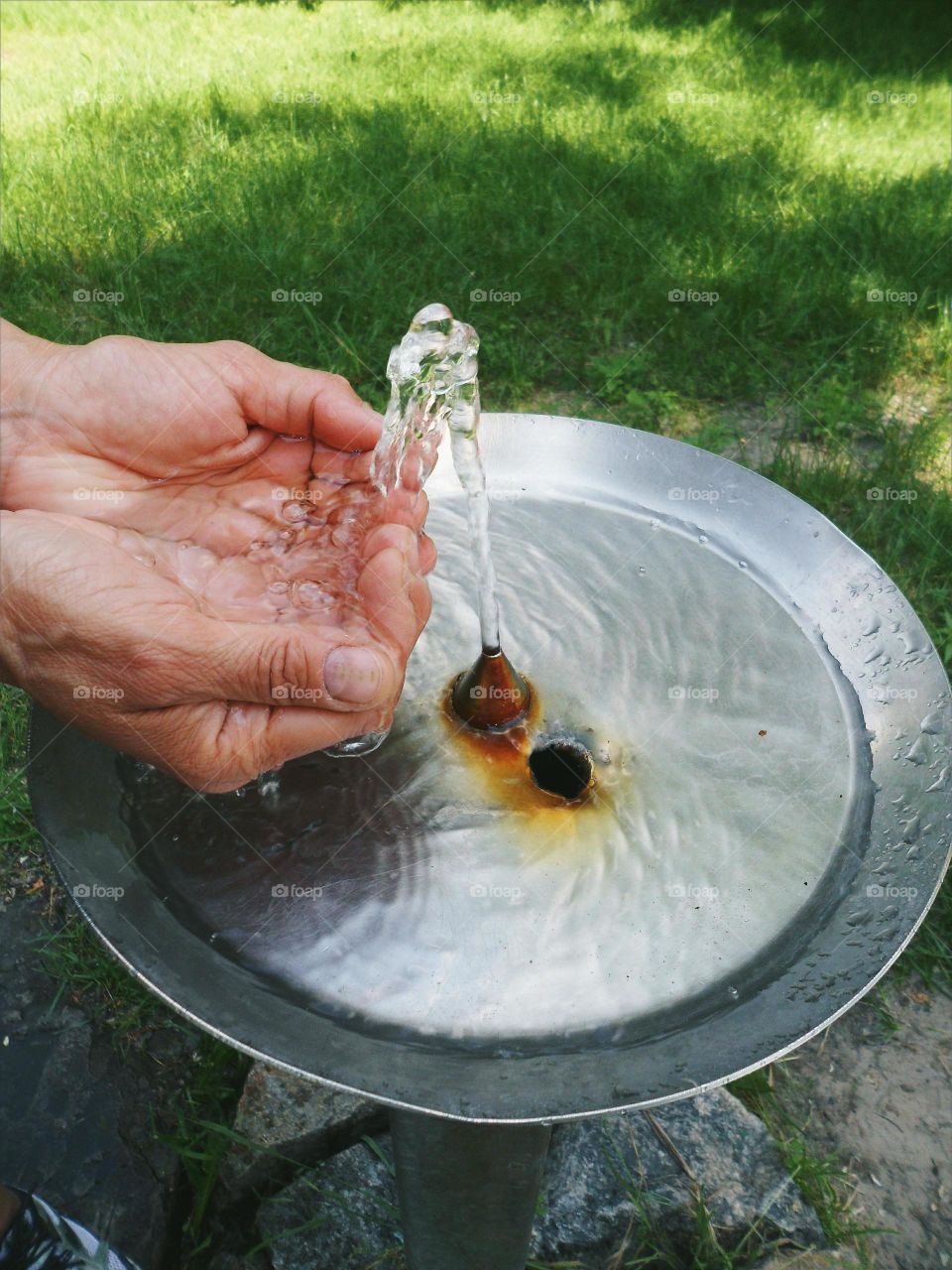 In the hands of women pour a stream of water from the fountain