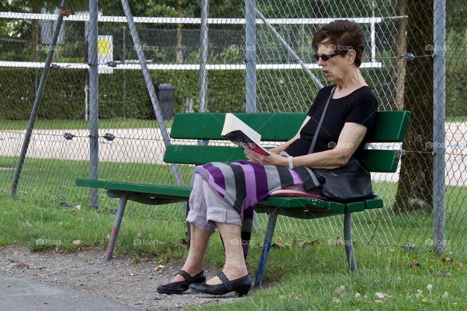 Senior woman reading a book in the park.