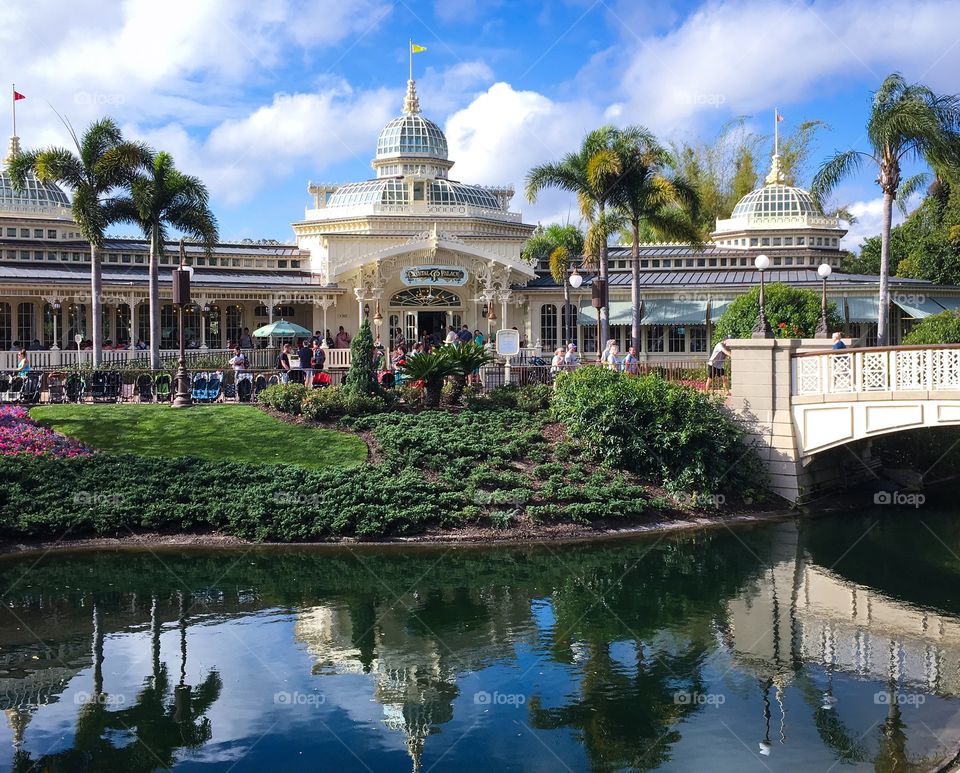 Looking across the lagoon at the Crystal Palace in the Magic Kingdom.  A beautiful day, bright blue sky with white wispy clouds and a warm sun.  