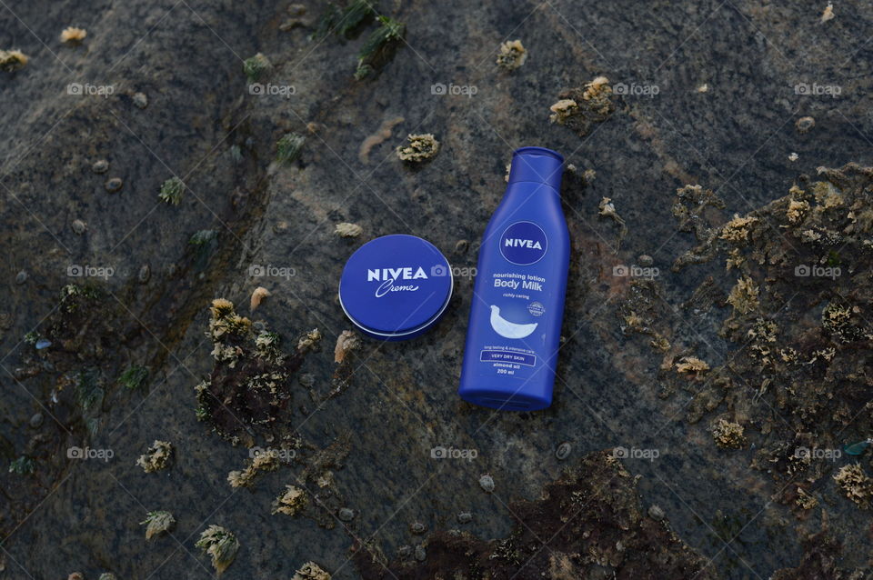 Nivea creme and Nivea body lotion are flaunted on the sea rock covered by beautiful Leathesia or Marine algae.