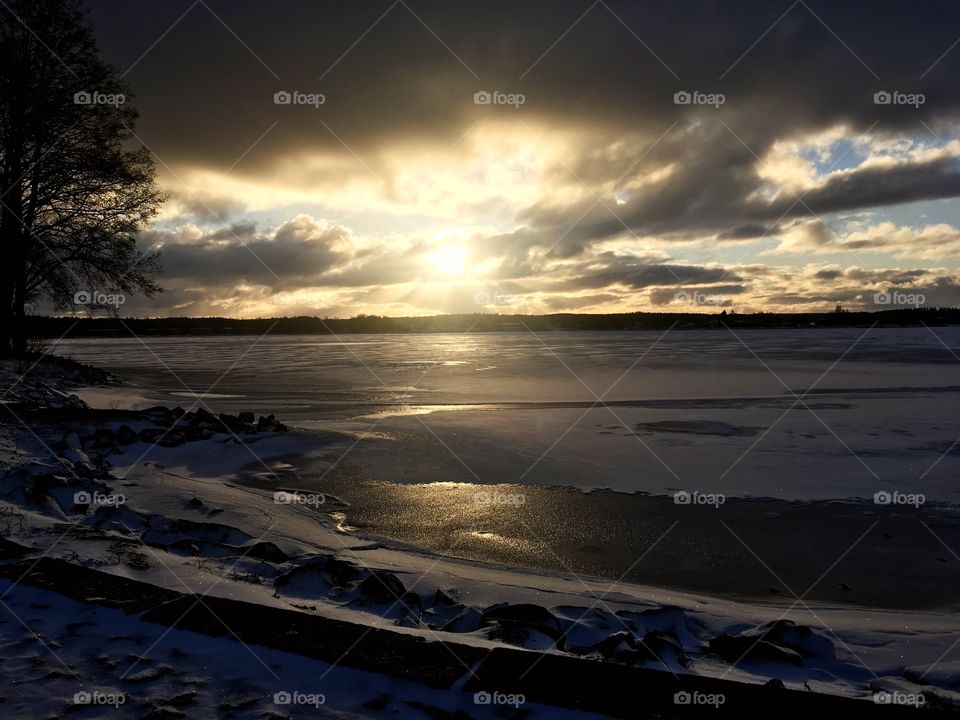 Sunsetting creates beautiful shadows and colors all around to the coastline. Cold winter weather and icy lake.