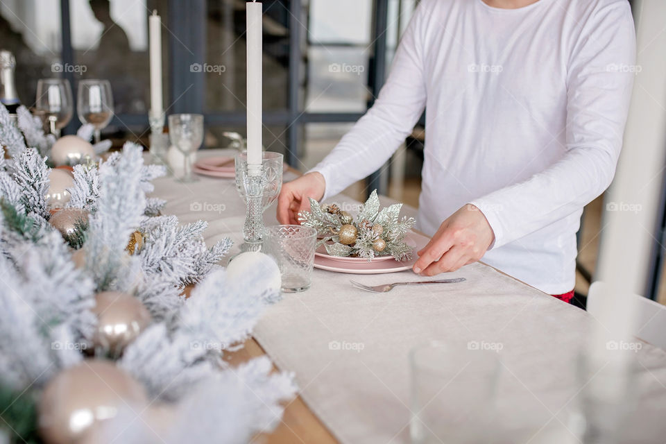 man sets a beautiful decorated winter table for a festive dinner.  Merry Christmas and Happy New Year.