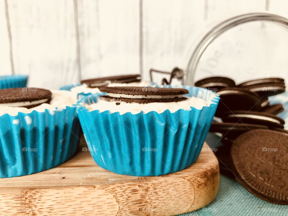 Oreo cookie ice cream cupcakes on a wooden board and white and blue background 