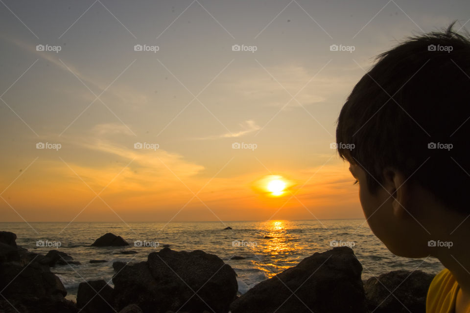 boy looking at sunset at the beach