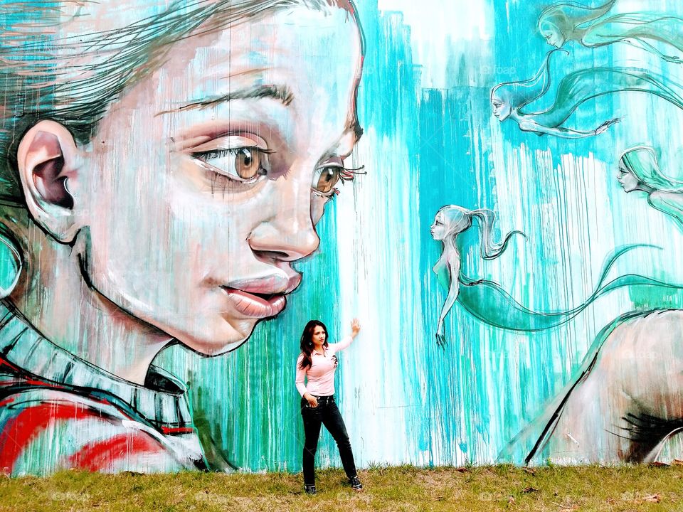Woman posing in front of mural
